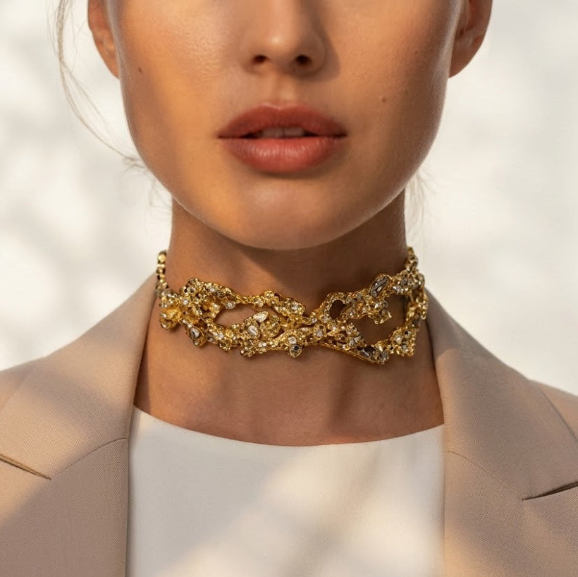 Close-up of a person wearing a gold necklace with a neutral background